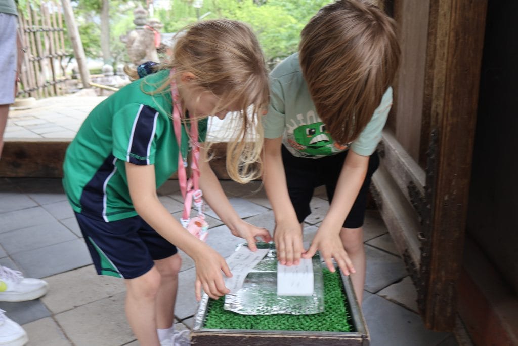 Two children taking part in an ice-block fortune telling activity at Himuro Shrine in Nara, Japan.