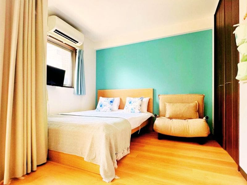 A bright vibrant hotel room in Juso AFP Apartment Hotel showing a double bed with an armchair