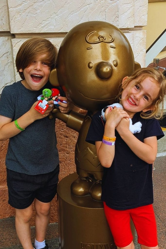 Philip and Lillia looking happy together standing next to a golden statue of Charlie brown holding toys