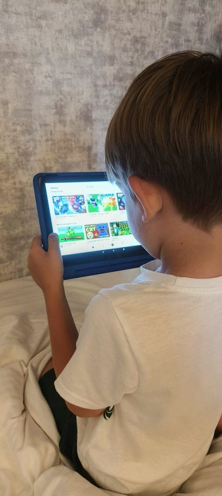 Young boy using an Amazon Fire Kids Tablet to browse educational games while travelling