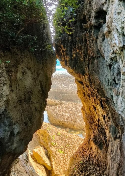 View through the Kissing Rocks at Eluanbi Lighthouse, revealing golden rocks and turquoise sea beyond.