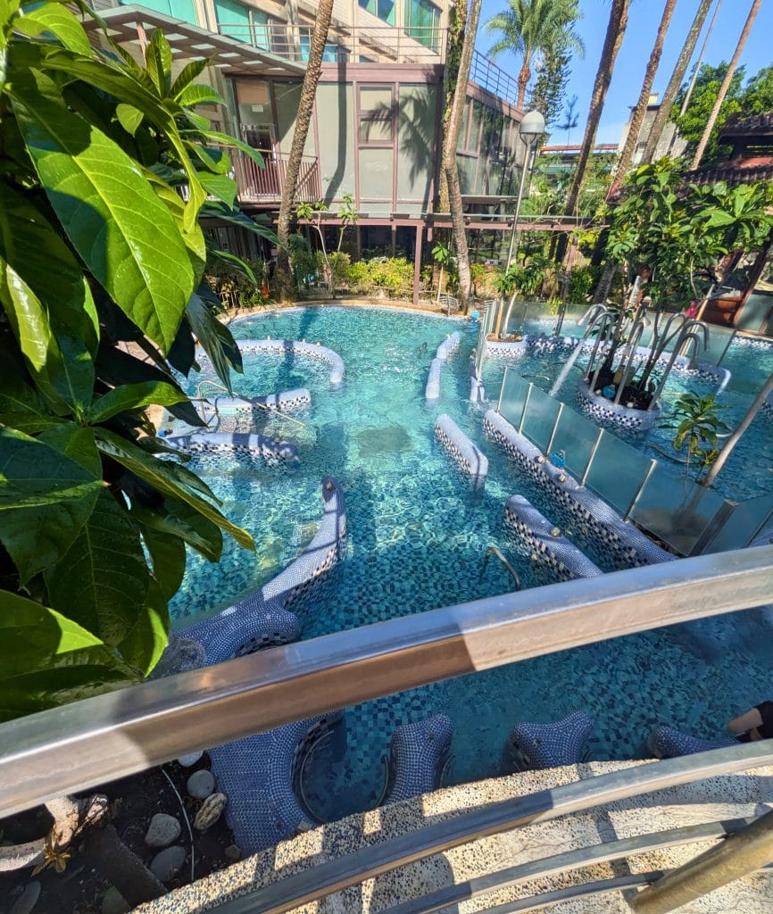 Outdoor hot spring pool at Art Spa Hotel in Jiaoxi, with tiled loungers, tropical plants, and a serene garden setting.