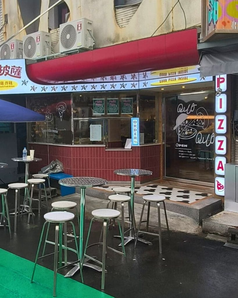 Outdoor seating at Quo Pizza on Kenting Night Market street, serving Western-style pizza and drinks in a casual setup