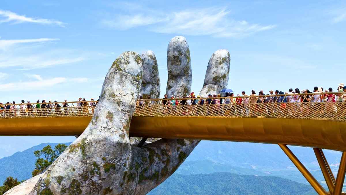 Golden Bridge at Ba Na Hills in Da Nang held by giant stone hands with tourists walking across