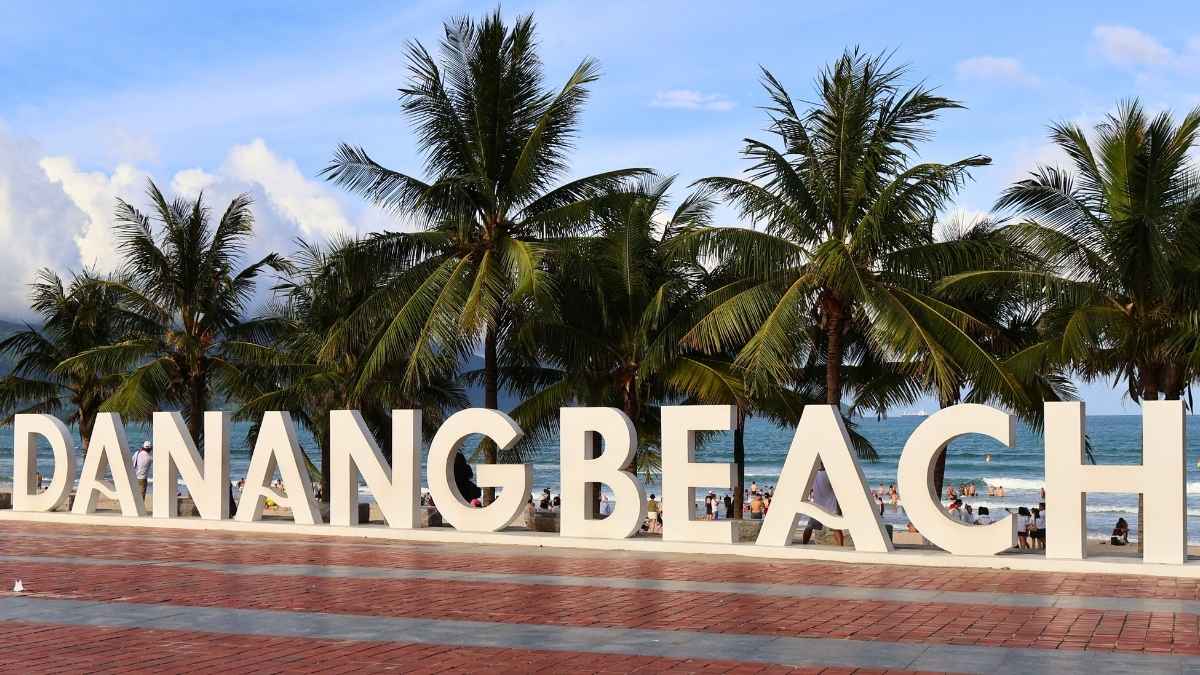 Da Nang Beach sign with palm trees and ocean backdrop, a popular family spot in central Vietnam
