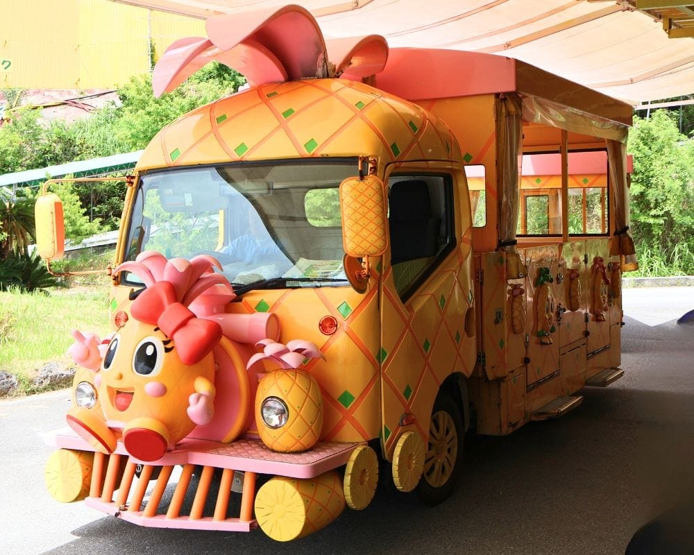 Colorful pineapple-themed tour bus at Nago Pineapple Park in Okinawa, Japan – fun family-friendly attraction for kids