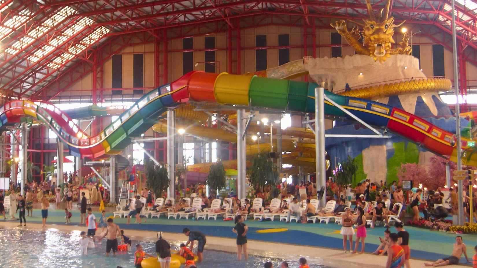 Indoor water park in Da Nang with colorful slides, dragon-themed decor, and families enjoying the pools.